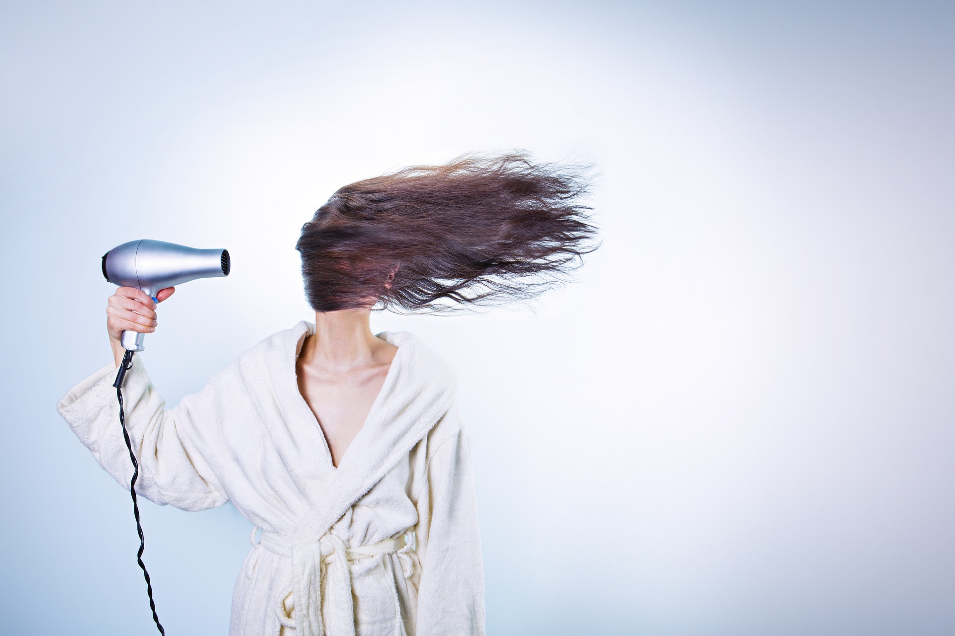Frau beim Föhnen - Haare fliegen zur Seite