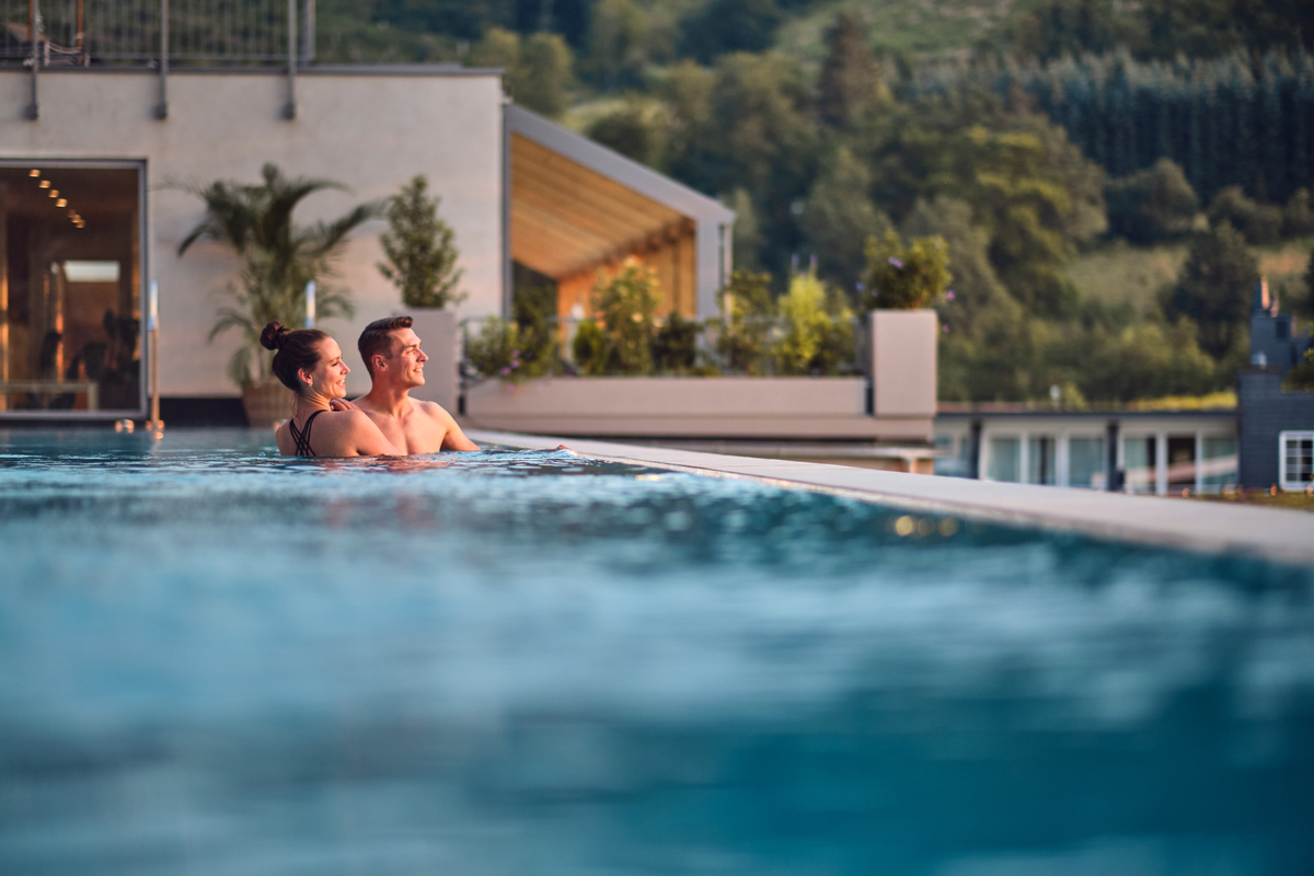 paar geniesst den sonnenuntergang im infinity-pool des hotel deimann