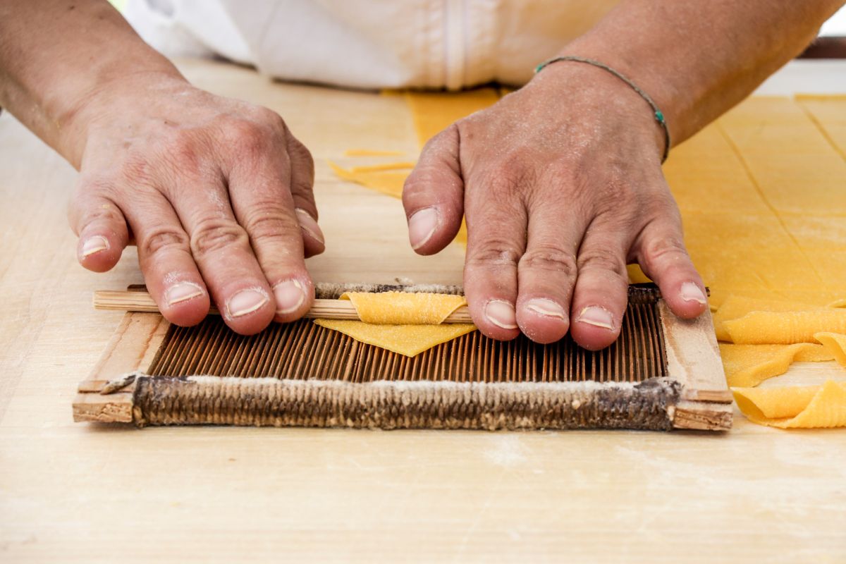 Frische Pasta wird über ein Brett gerollt