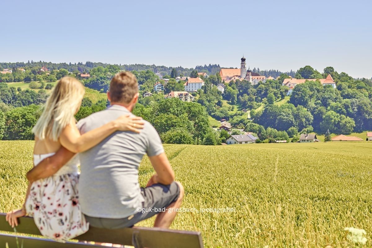 Paar sitzt auf Bank mit Blick auf Bad Griesbach